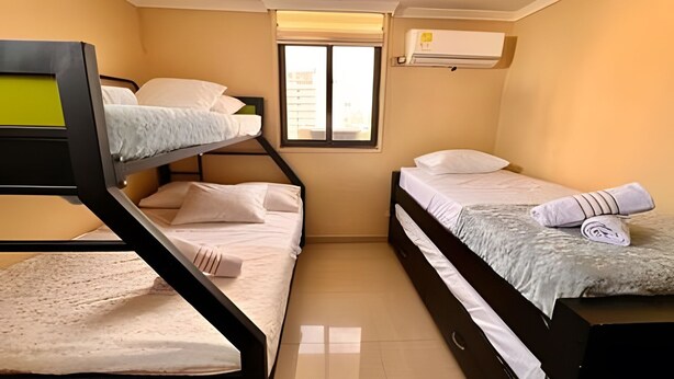 Habitación pequeña con literas, una ventana y aire acondicionado.