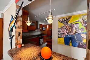 Eine Küche mit einer Arbeitsplatte aus Granit, einer Mikrowelle und einer Pendelleuchte.