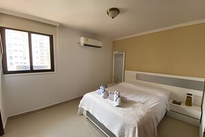 Une chambre d’hôtel équipée d’un lit, d’une table de chevet, d’une fenêtre et d’un appareil de climatisation.