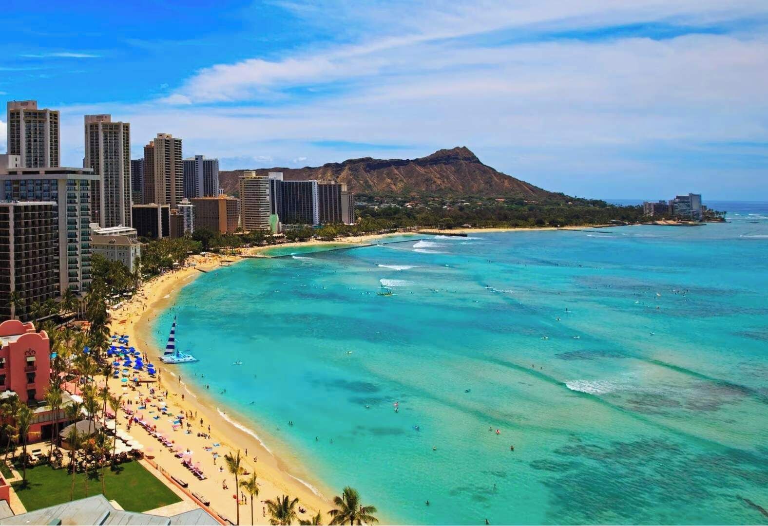 A coastal cityscape with a beach, high-rise buildings, and a mountain in the background.