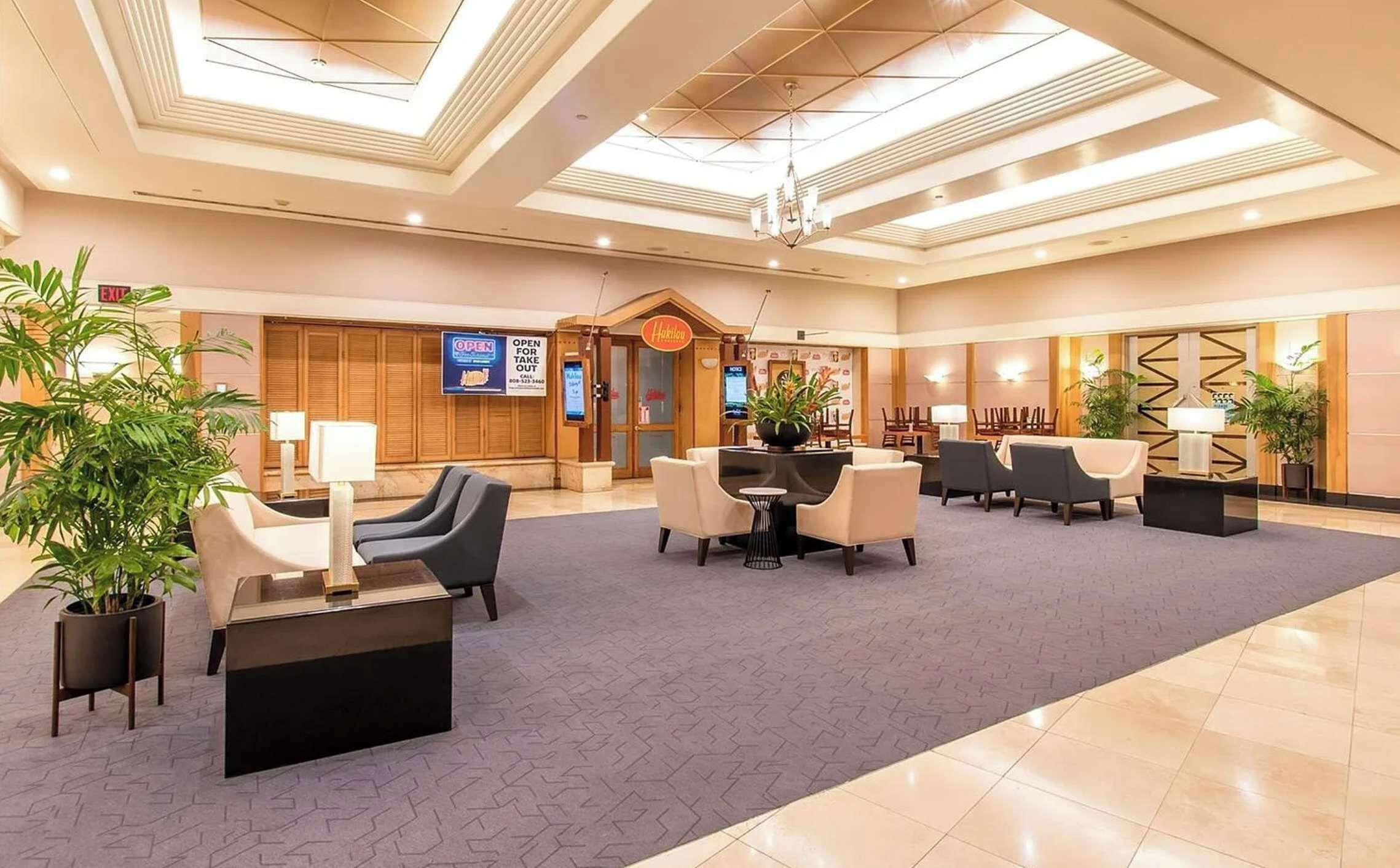 A spacious lobby with a high ceiling, a central seating area, and a reception desk.