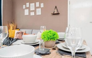 A dining table set with plates, glasses, and a potted plant. - Stylish 3BR Home Near Nec, Bhx, HS2 & JLR (Birmingham)