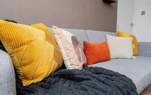 A grey sofa with a black blanket and three pillows in different colors. - Stylish 3BR Home Near Nec, Bhx, HS2 & JLR (Birmingham)