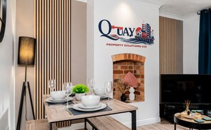 A modern living room with a dining area, a fireplace, and a television. - Stylish 3BR Home Near Nec, Bhx, HS2 & JLR (Birmingham)