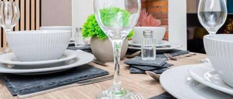 A dining table set with white plates, bowls, and a glass of water.