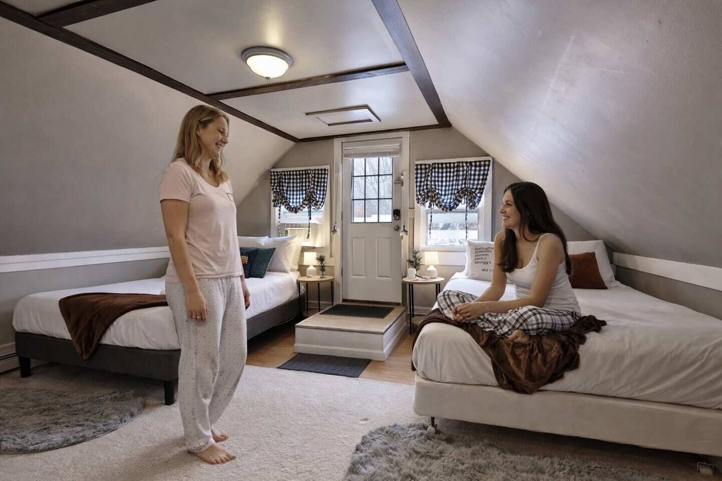 A bedroom with two beds, a door, and a small table with a lamp.