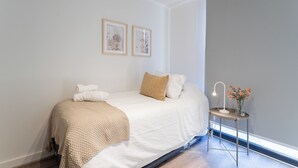 A bedroom with a bed, pillows, a bedside table with a lamp, and framed pictures on the wall. - R. Lyon Apartments by Andes STR (Providencia)