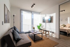 A modern living room with a sofa, coffee table, and a flat-screen TV mounted on the wall. - R. Lyon Apartments by Andes STR (Providencia)