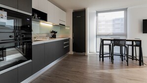 A modern kitchen with dark cabinetry, a built-in oven, and a dining area with a table and chairs. - R. Lyon Apartments by Andes STR (Providencia)