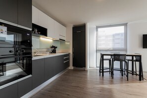 A modern kitchen with dark cabinetry, a built-in oven, and a dining area with a table and chairs. - R. Lyon Apartments by Andes STR (Providencia)