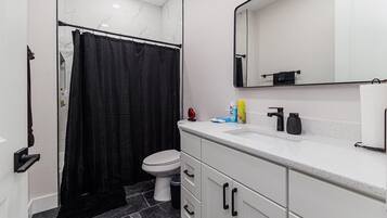 A bathroom with a toilet, a sink, a mirror, and a shower curtain.
