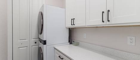 Una cocina compacta con armarios blancos, horno empotrado y encimera.