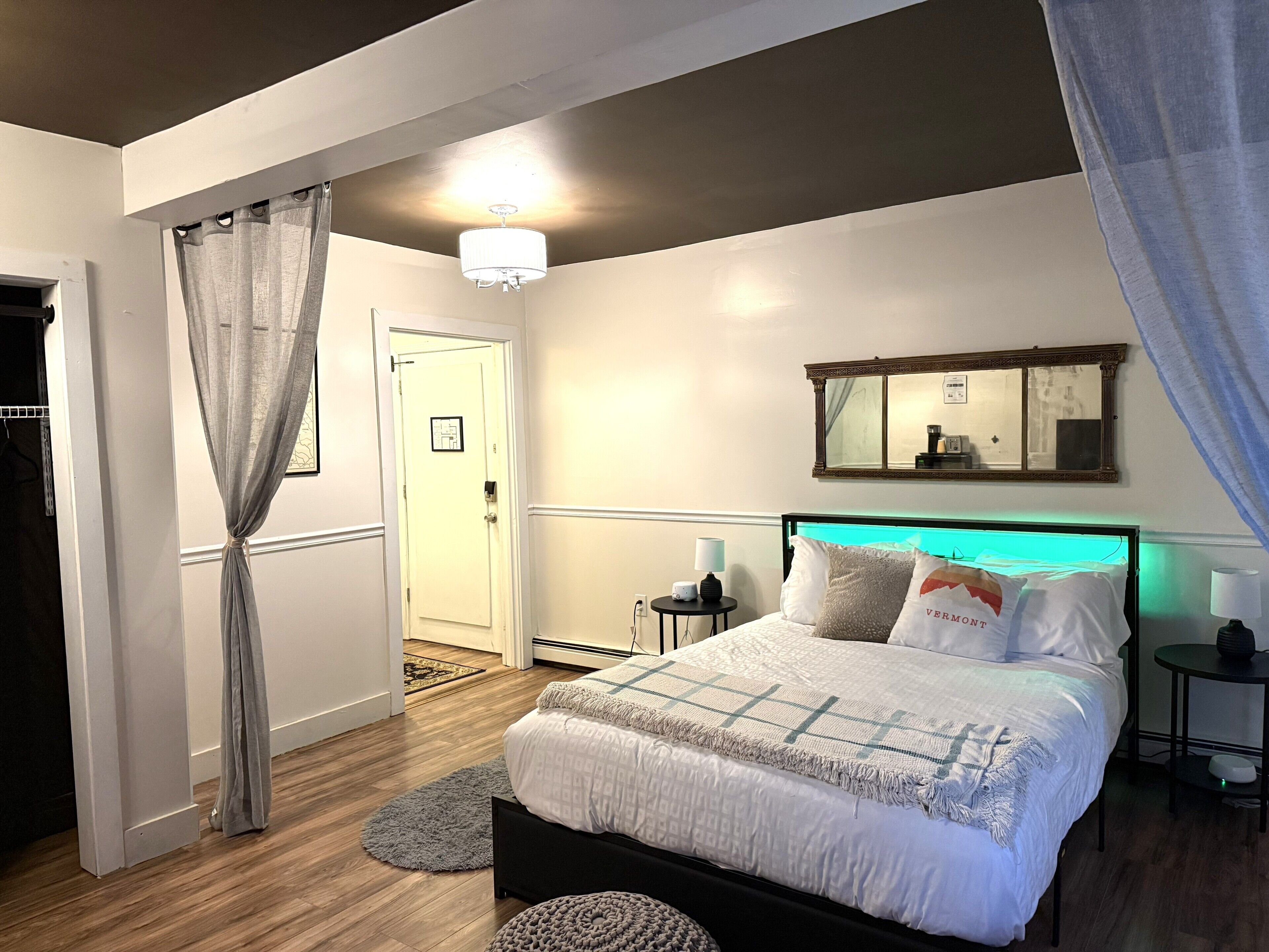 A bedroom with a bed, bedside tables, a mirror, and a door.