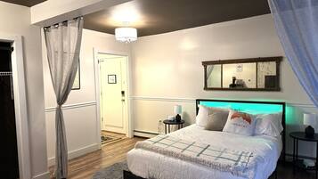 A bedroom with a bed, bedside tables, a mirror, and a door.