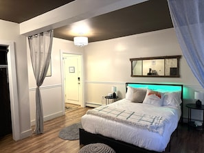 A bedroom with a bed, bedside tables, a mirror, and a door. - Bridgewater Living - Woodstock Suite (Bridgewater)