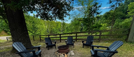 An outdoor seating area with Adirondack chairs arranged around a fire pit.