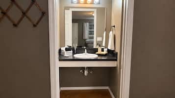 A bathroom with a vanity, mirror, and lighting.