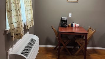 A dining area with a table, chairs, a coffee maker, and a wall-mounted picture.