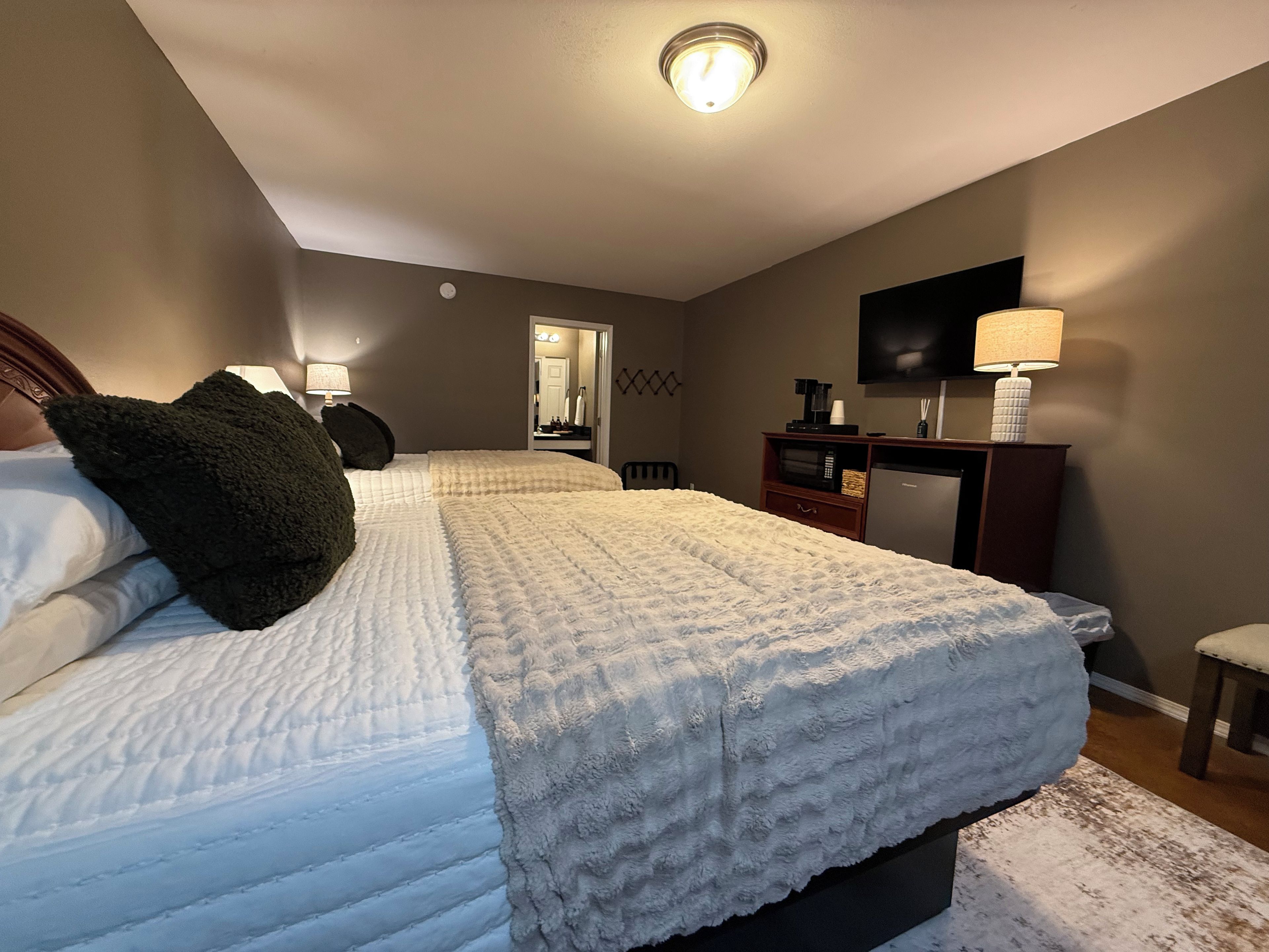 A hotel room with a bed, a desk, a chair, a television, and a mirror.