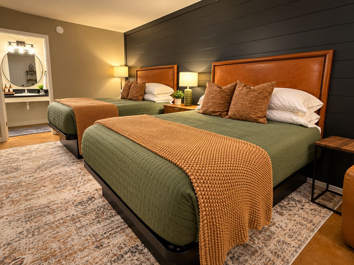 Habitación de hotel con dos camas, un espejo grande y una tocador con artículos de aseo.