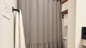 Une salle de bain avec un rideau de douche à rayures, des serviettes blanches, des toilettes et un carrelage à motifs.