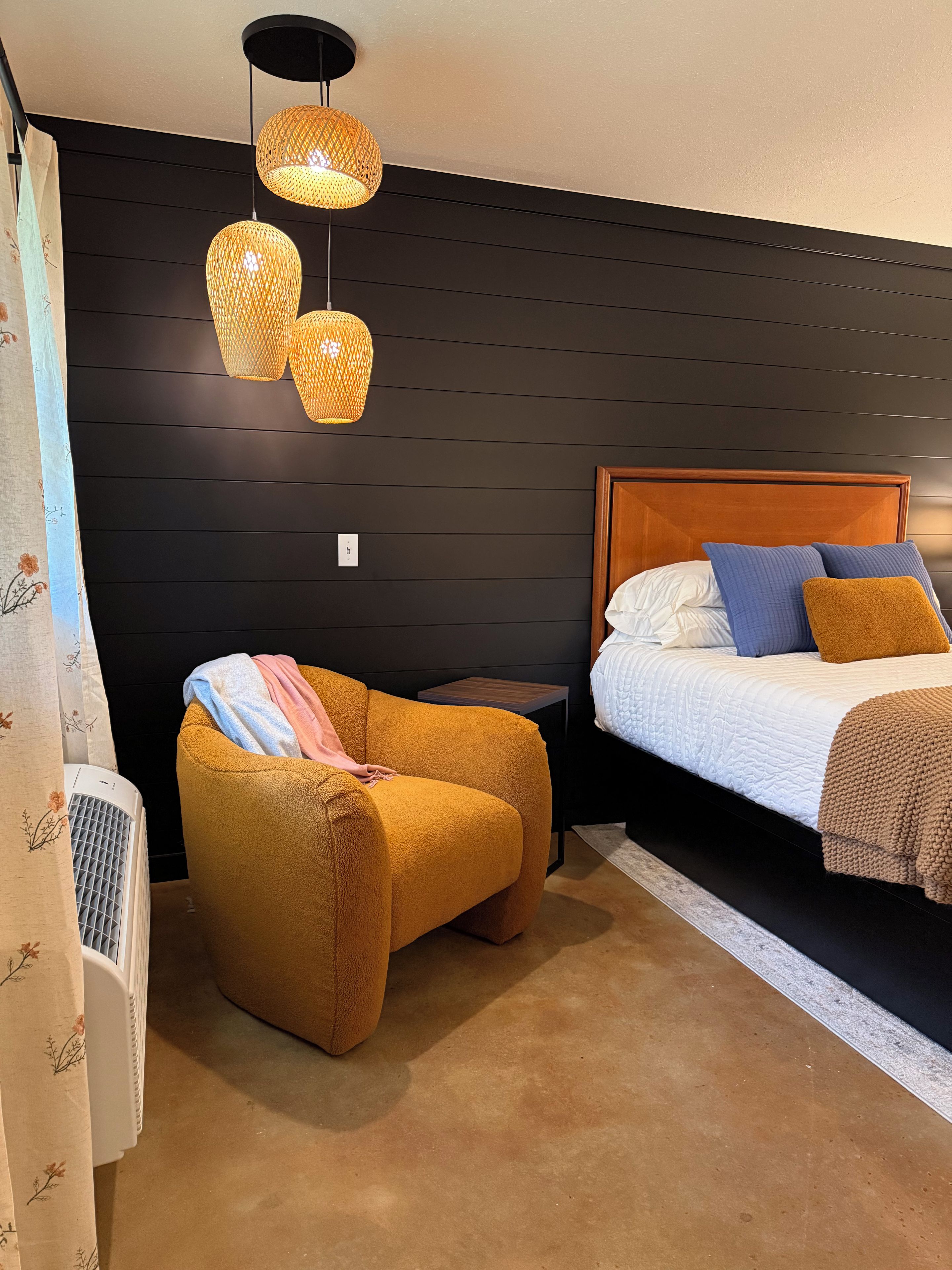 Una habitación con una cama, una silla y una mesita de noche.