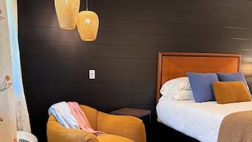 Una habitación con una cama, una silla y una mesita de noche.