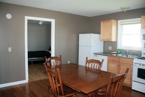 A compact kitchen with a dining area, wooden cabinets, a refrigerator, and a window providing natural light.