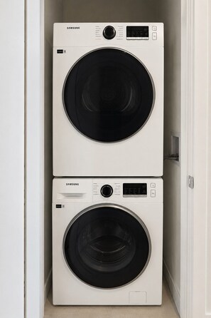 Deux machines à laver Samsung, l’une sur l’autre, dans un couloir étroit.