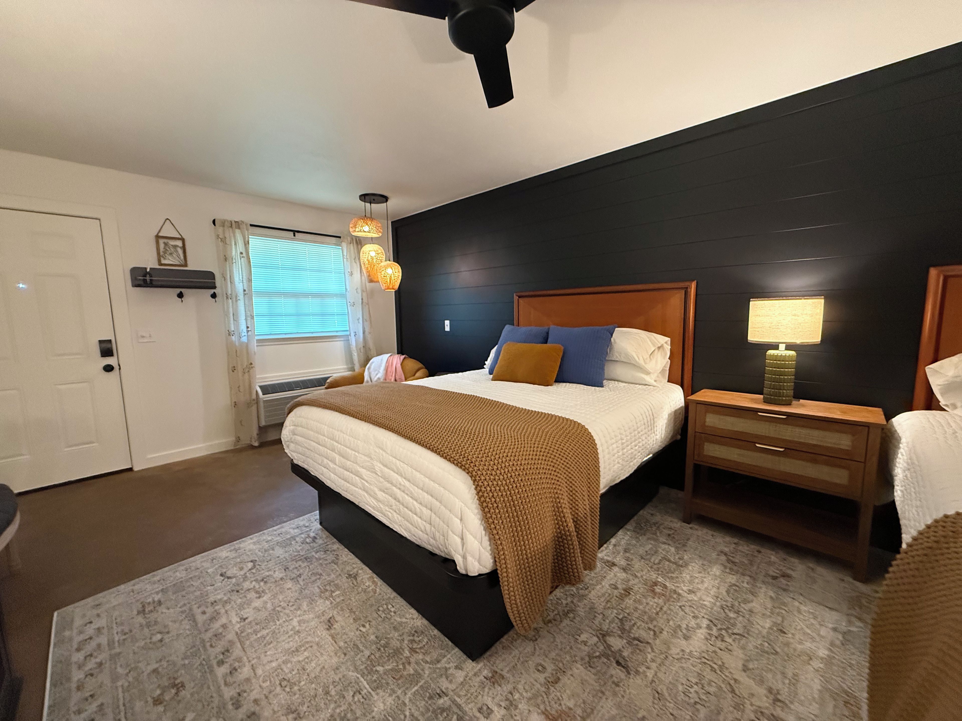Une chambre à coucher avec un lit, des tables de chevet, une lampe et un ventilateur de plafond.