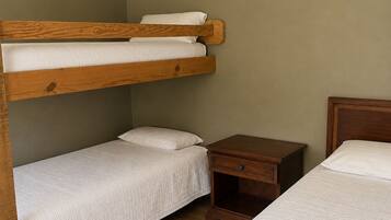 Dormitorio con literas, cabecera de madera, mesita de noche y velador.