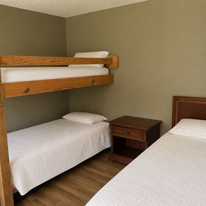A bunk bed room with a wooden headboard, a bedside table, and a nightstand. - Welcome to The Eddy, our family-friendly room at The Lodge on Ten (TAHLEQUAH)