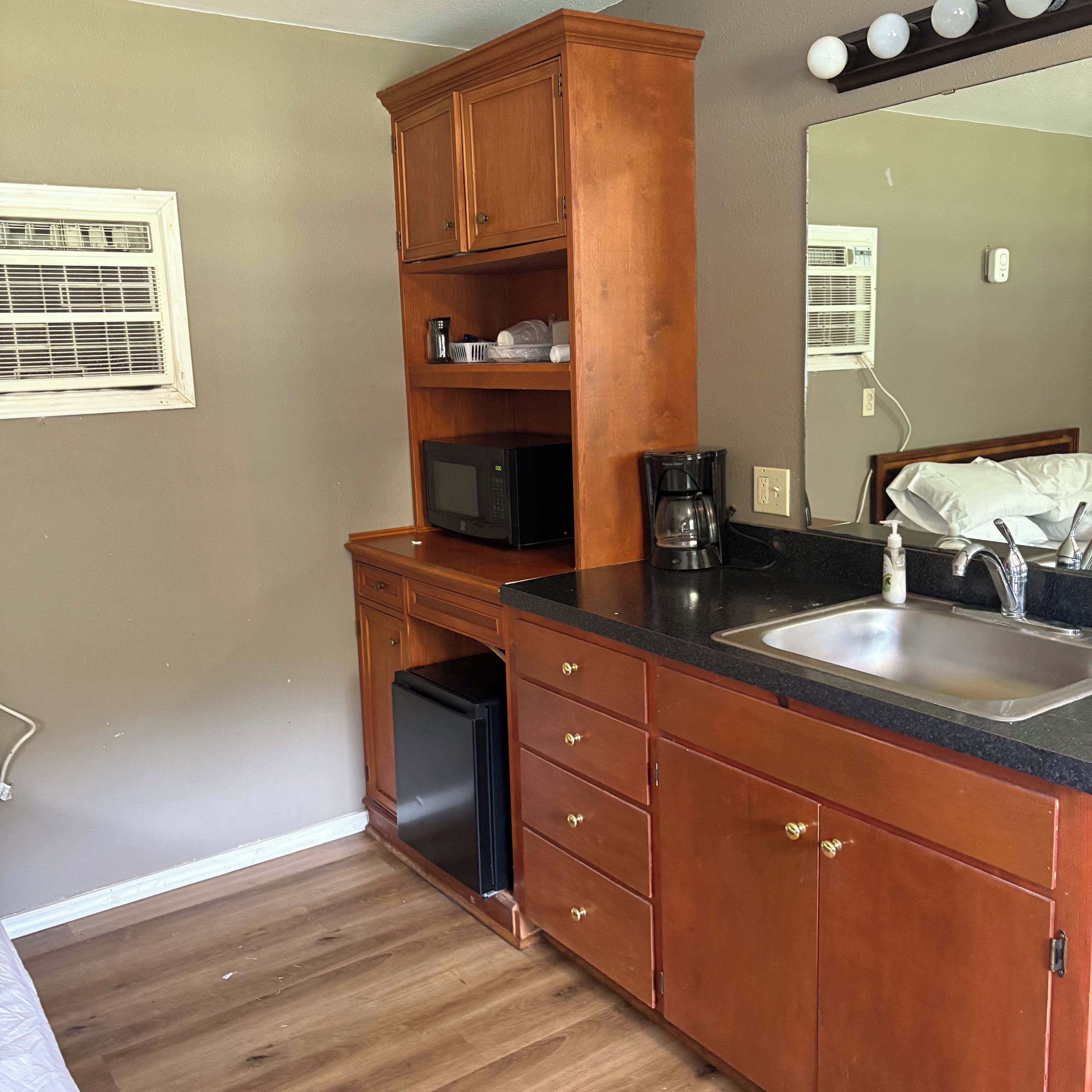 Cocina compacta con microondas, cafetera y lavamanos.