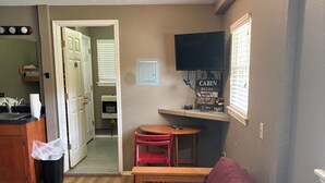 A compact living space with a kitchenette, a sofa, a dining table, and a television mounted on the wall. - Welcome to The Eddy, our family-friendly room at The Lodge on Ten (TAHLEQUAH)