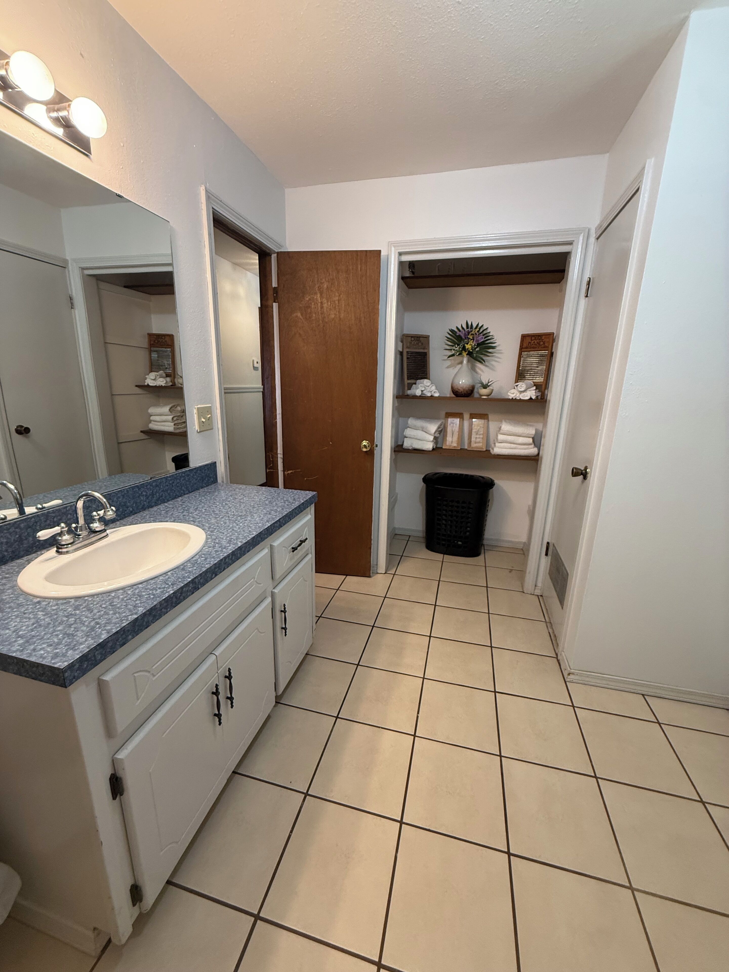 Une salle de bain équipée d’un lavabo, d’un miroir et d’un espace pour ranger les serviettes.
