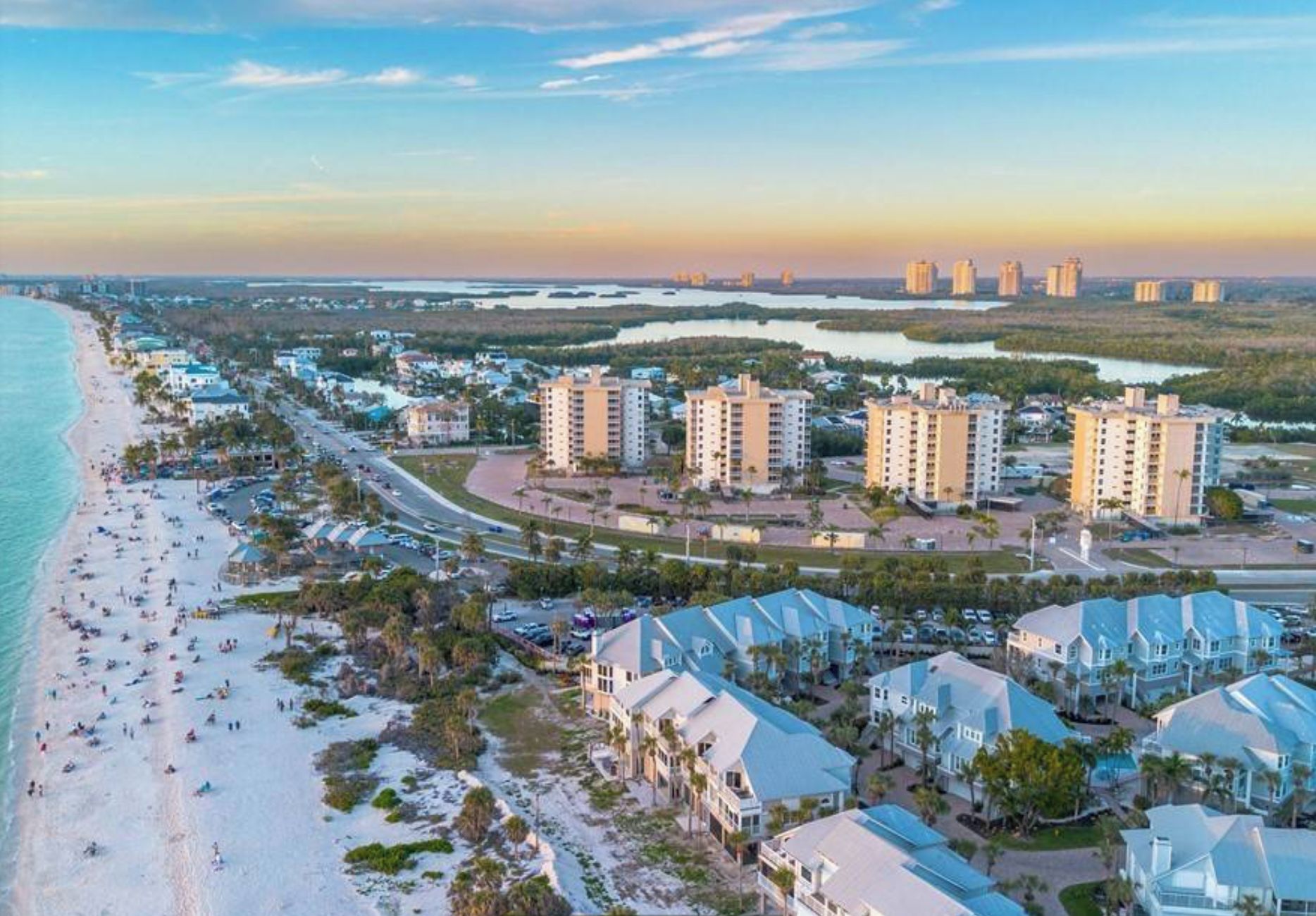 A coastal residential area with beachfront properties, a road, and a marina.