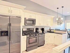 A modern kitchen with stainless steel appliances, white cabinetry, and a built-in oven. - Downtown Apt w/ Balcony & Free Parking (Geneva)