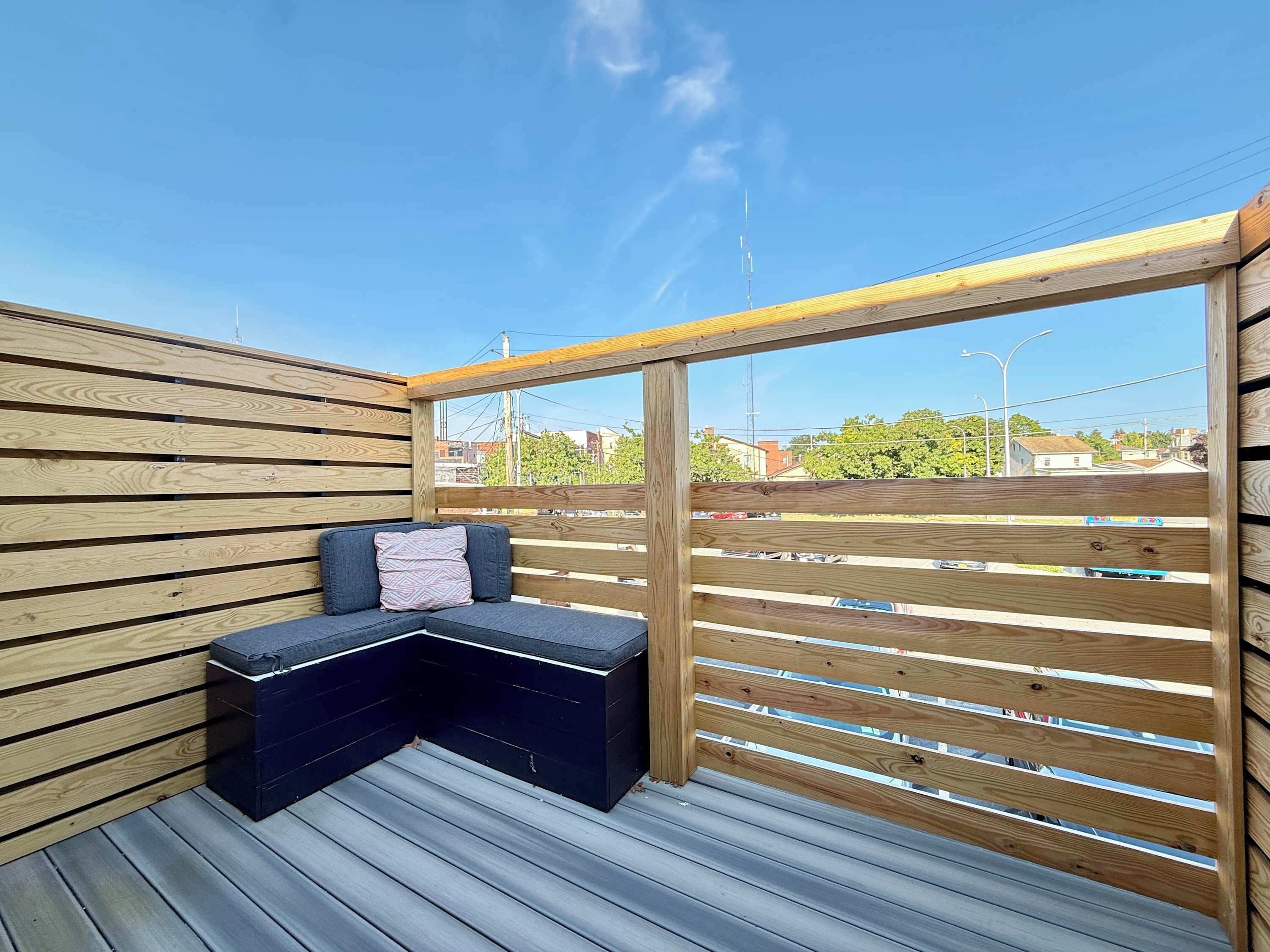A wooden deck with a built-in bench and a view of the surrounding area.