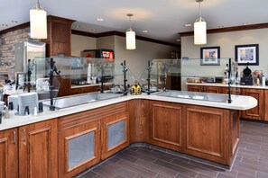 A modern kitchen with wooden cabinetry, a central island with a glass barrier, and overhead pendant lighting.