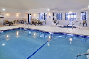 An indoor swimming pool with lounge chairs and a lifeguard station.