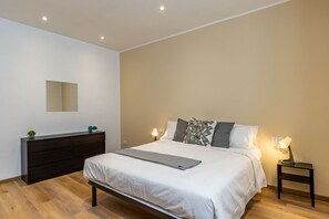 Ein Schlafzimmer mit einem Bett, Nachttischen, einem Schminktisch und einem Spiegel.