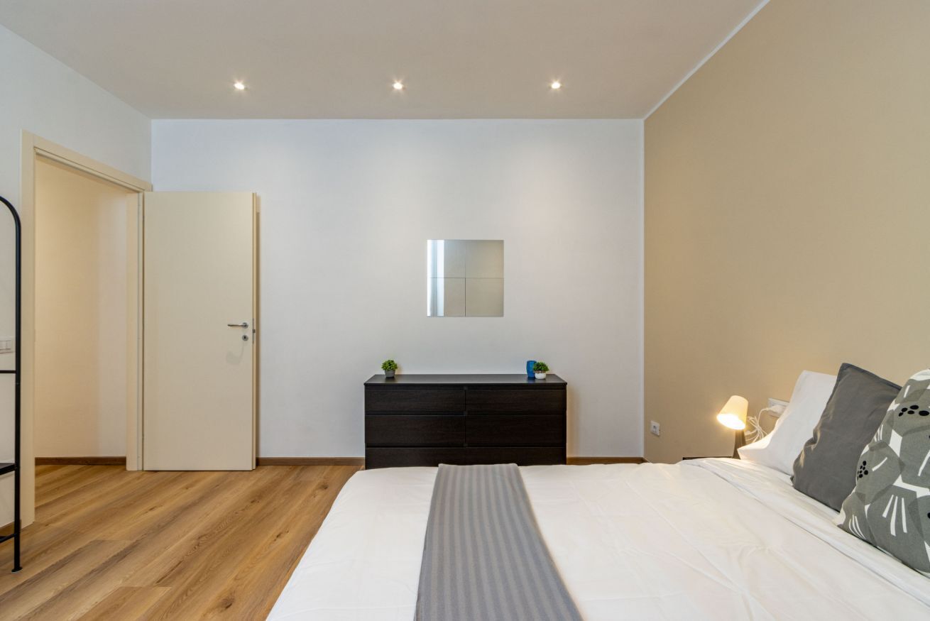 Ein Schlafzimmer mit Bett, Kommode, Spiegel und Nachttisch.