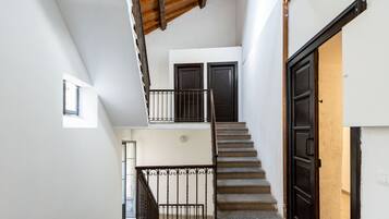Una scala con ringhiera in metallo conduce al secondo piano, una porta e una piccola finestra.