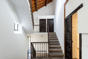 Eine Treppe mit Metallgeländer führt zu einer zweiten Etage, einer Tür und einem kleinen Fenster.