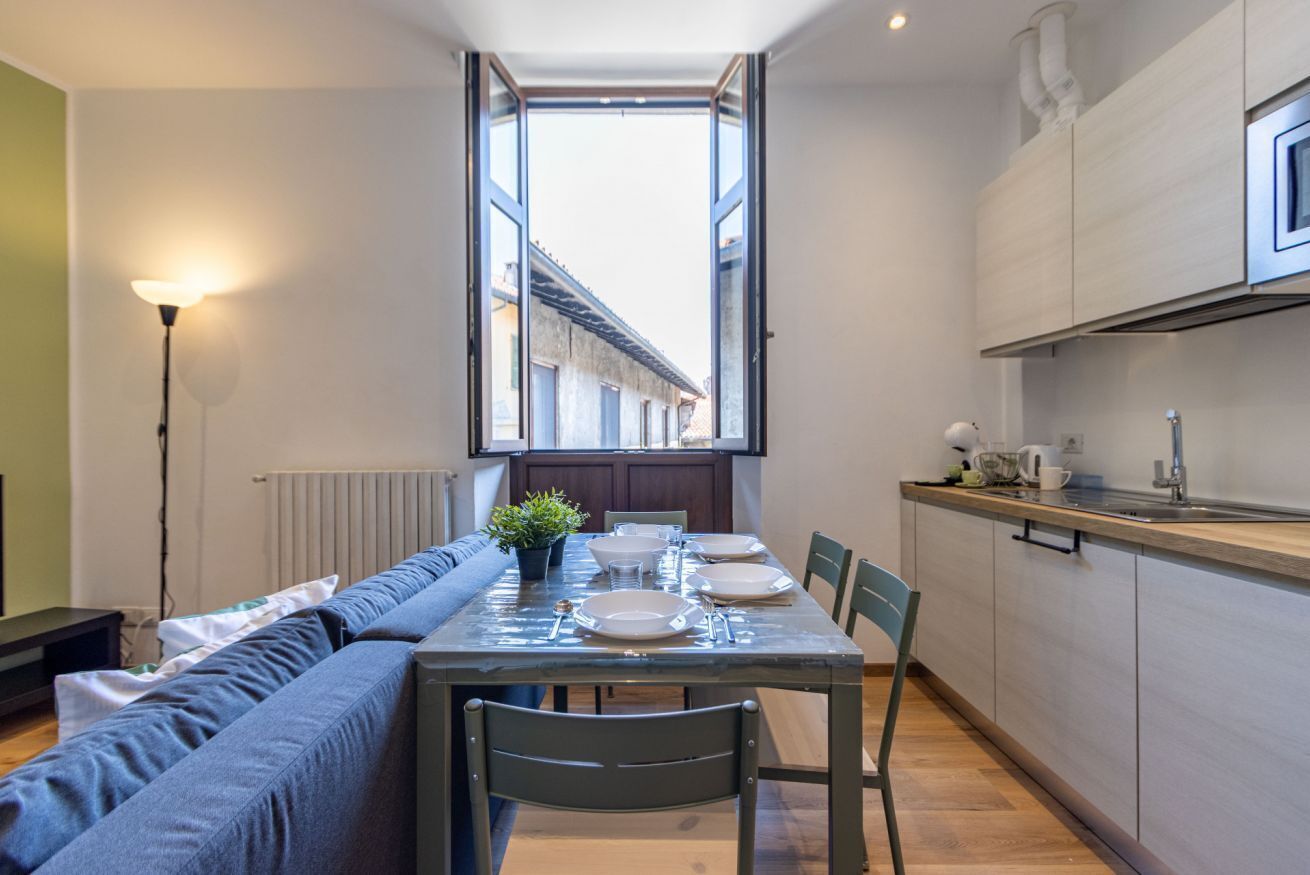Eine moderne Küche mit Esstisch für vier Personen, einem großen Fenster und einem eingebauten Backofen.