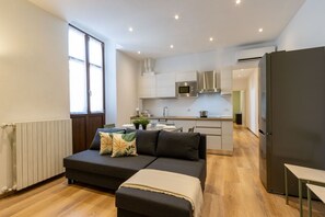 Eine moderne Wohnung mit einer Küchenzeile, einem Sofa, einem Essbereich und einem großen Fenster.