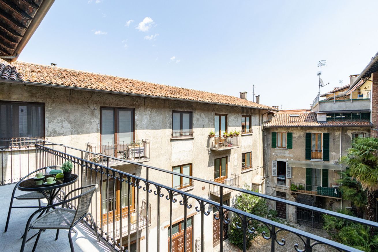 Ein Balkon mit Tisch und Stühlen, der auf einen Innenhof mit Gebäuden blickt.
