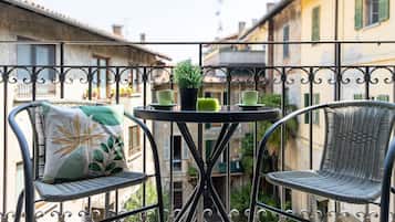 A balcony with wicker chairs, a small round table, and a potted plant.