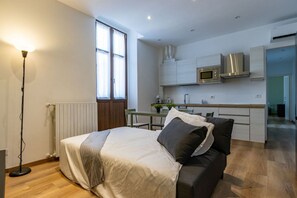Un dormitorio moderno con una cama, una lámpara de noche y vistas a una zona de cocina.