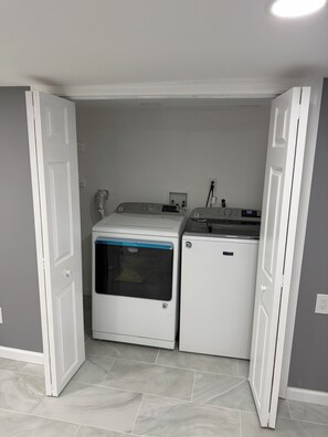 A laundry room with two white appliances, one with a blue stripe, and a tiled floor. - Welcome to our comfortable and private 1bdrm basement aprt located in Belleville (Belleville)